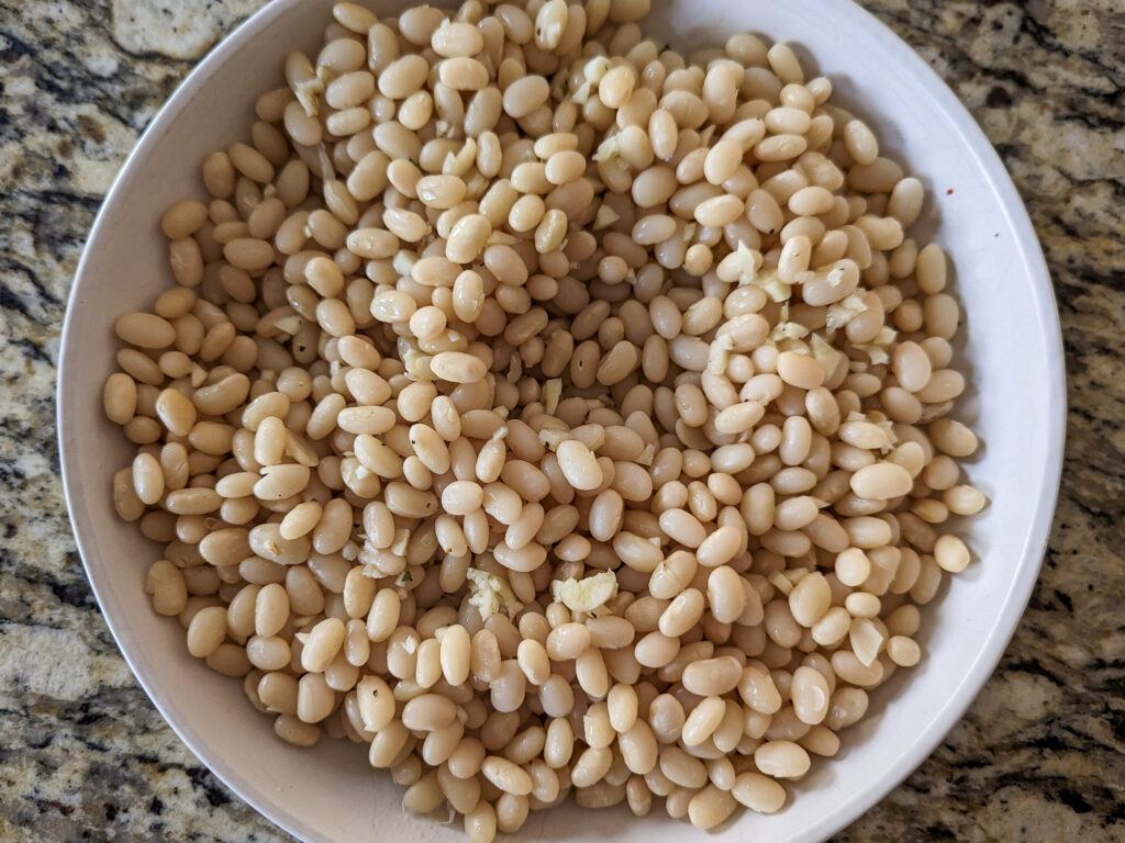 White beans on a serving plate with the dressing over it.