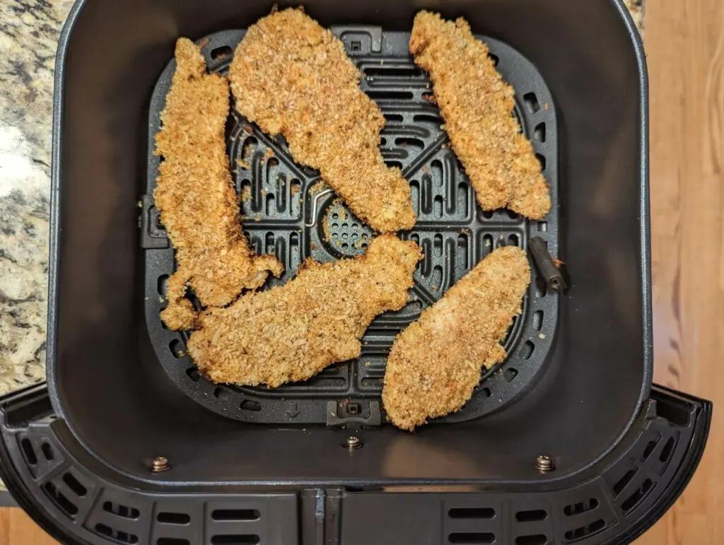 The chicken tenders flipped in the air fryer basket.