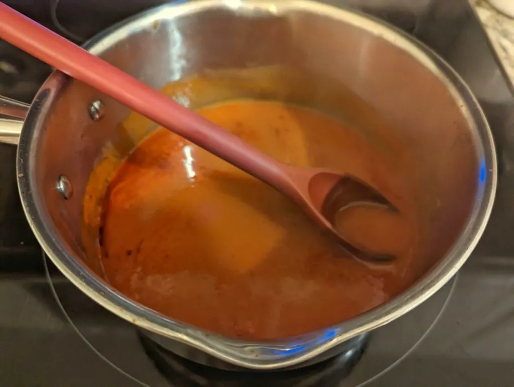 Buffalo sauce and butter heating in a saucepan on the stove.