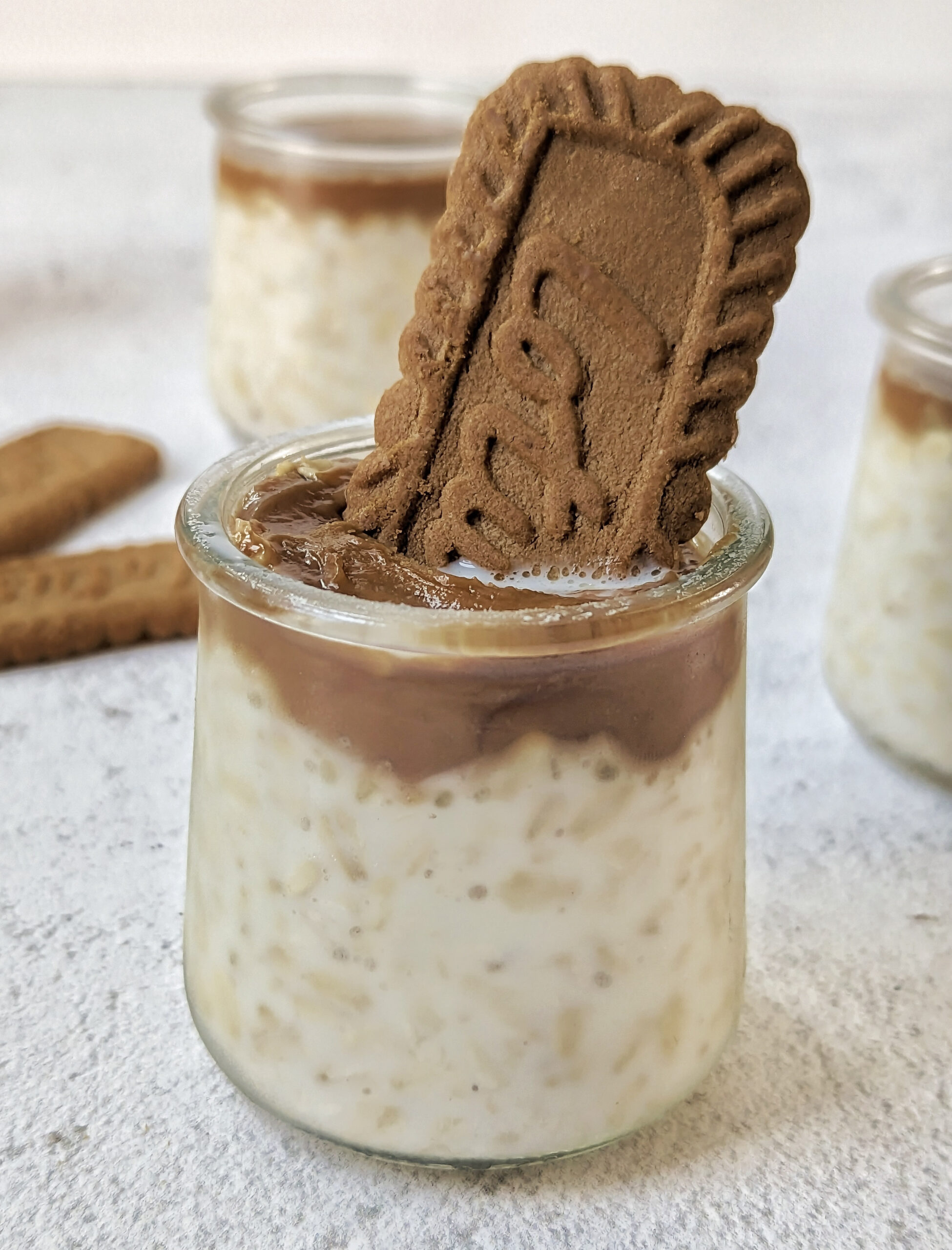 A cup with Biscoff overnight oats topped with Biscoff cookie butter and garnished with a Biscoff cookie.
