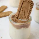 A cup with Biscoff overnight oats topped with Biscoff cookie butter and garnished with a Biscoff cookie.