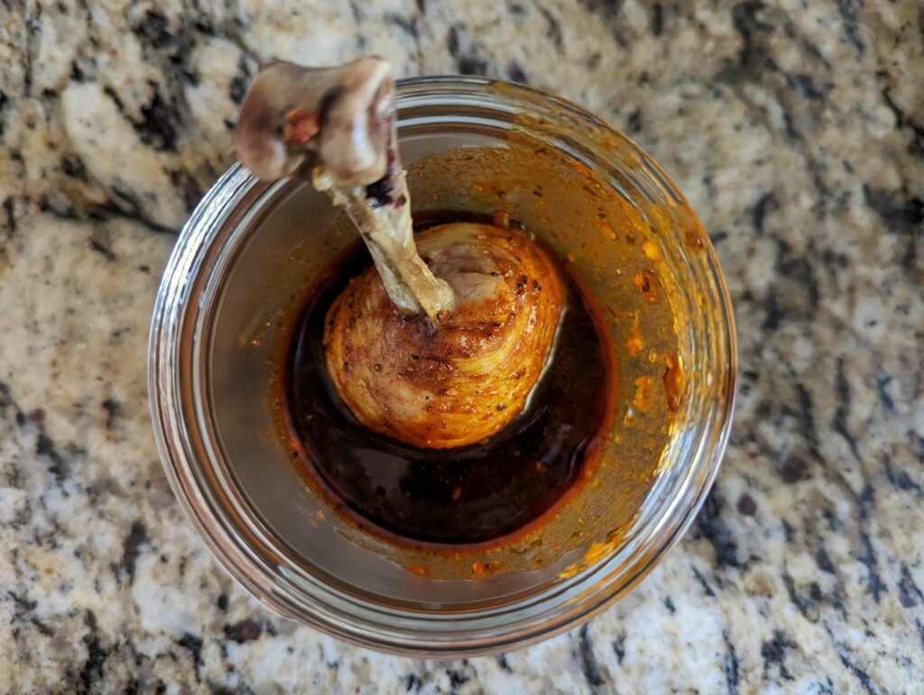 A drumstick inside the cup of sauce.