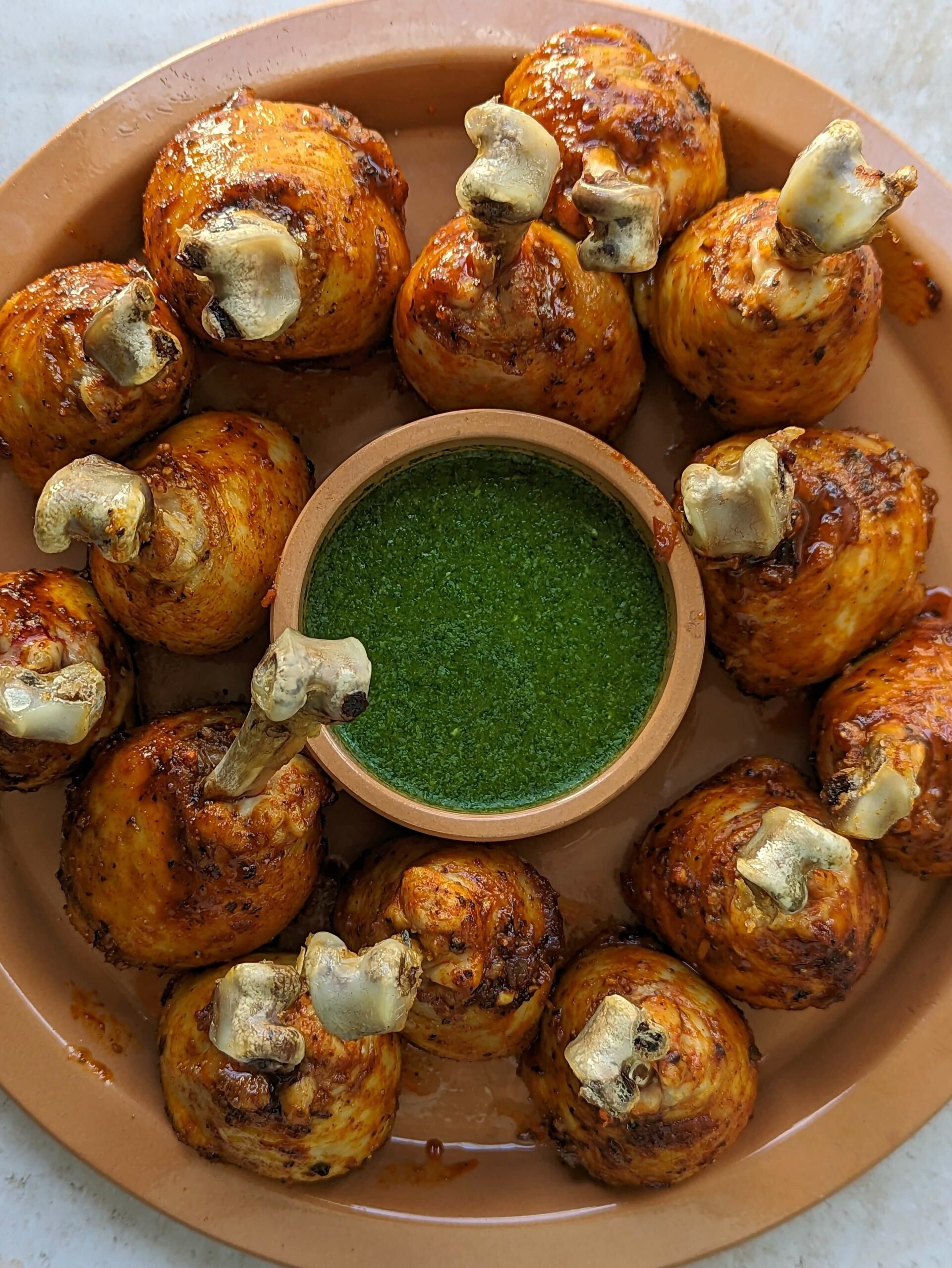 Chicken lollipops on a serving dish with cilantro chutney.