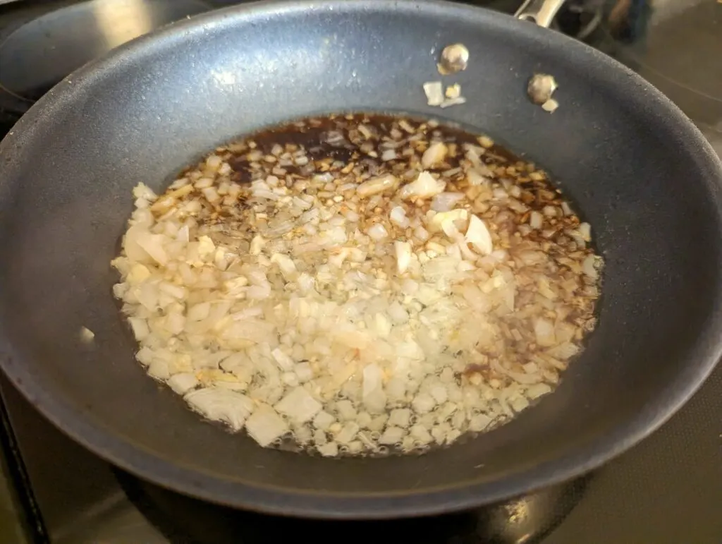 Oil, onions, garlic, and soy sauce sautéing in a pan.