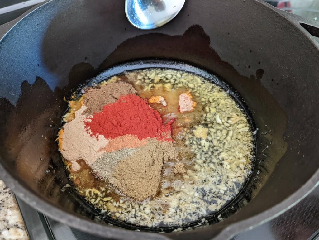 Spices added to the cooking garlic in a dutch oven. 