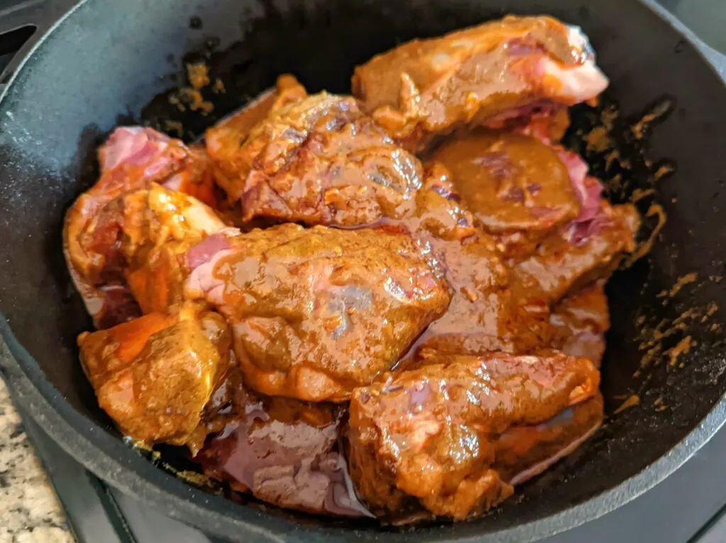 Beef shanks and bones combined with the spices, oil, and garlic inside the dutch oven. 