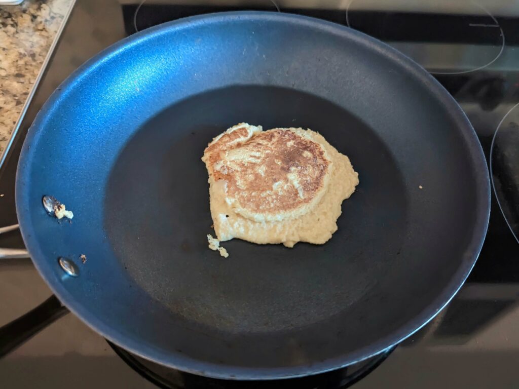 Oat milk pancakes cooking in a frying pan. 