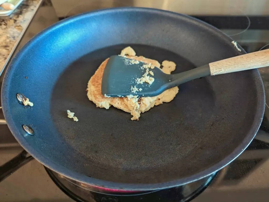 Oat milk pancakes flipped and cooking in a frying pan. 