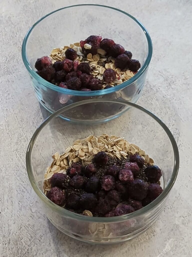 Fill two cups with oats, chia, seeds, and frozen blueberries.