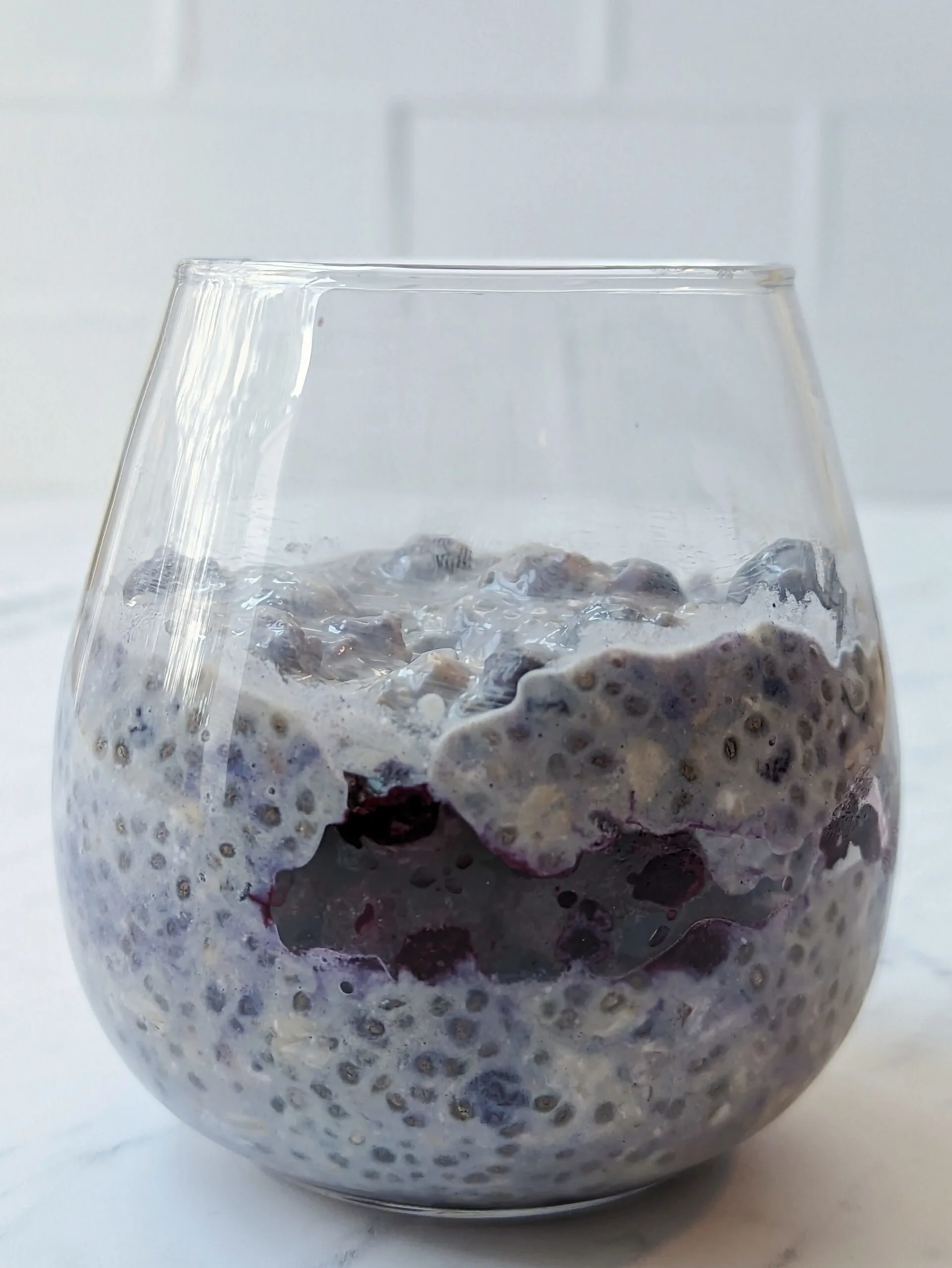 A side view of overnight oats with frozen fruit.