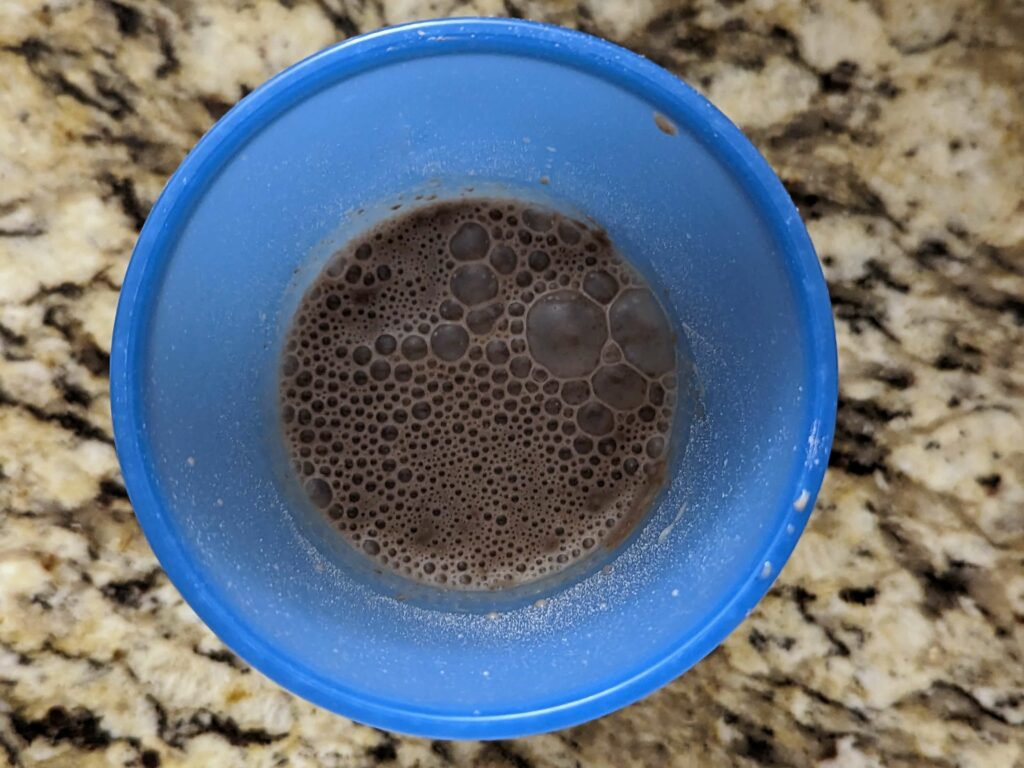 Almond milk and protein powder combined in a cup.