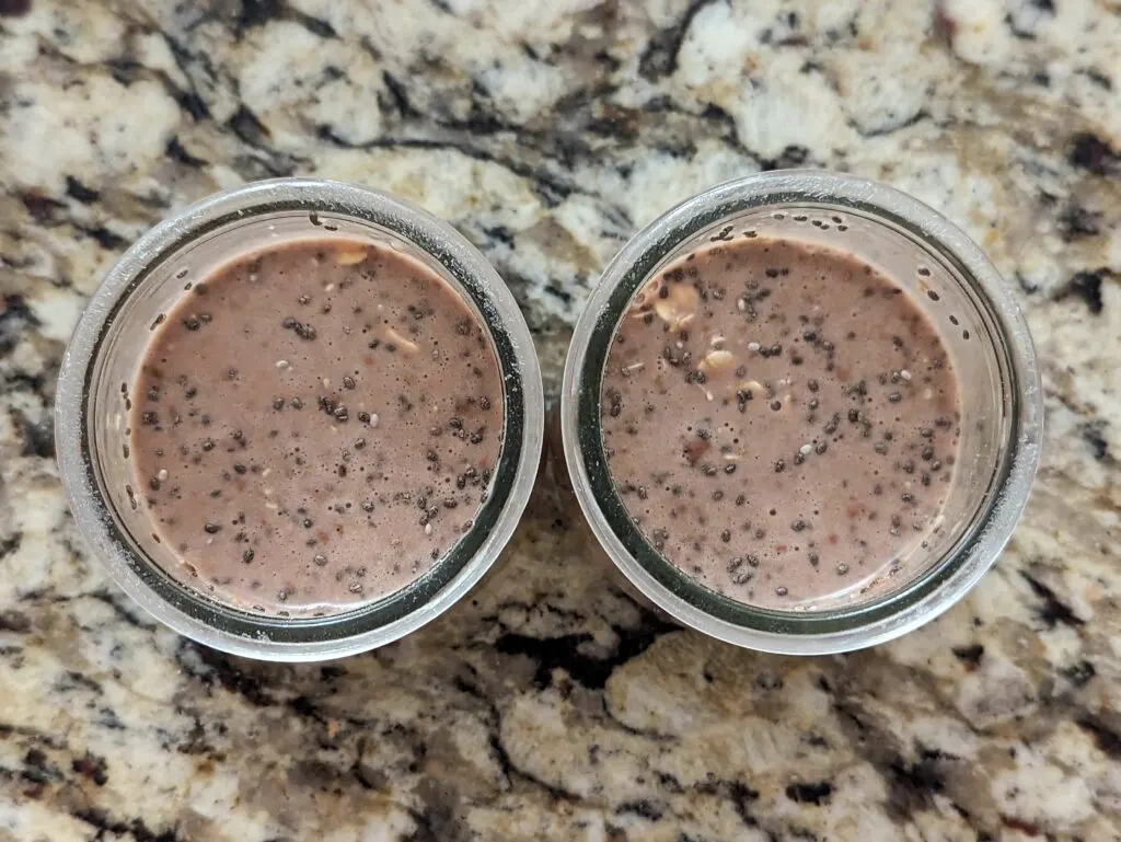 Protein powder and milk added to the oats and chia seeds in the glass jars. 
