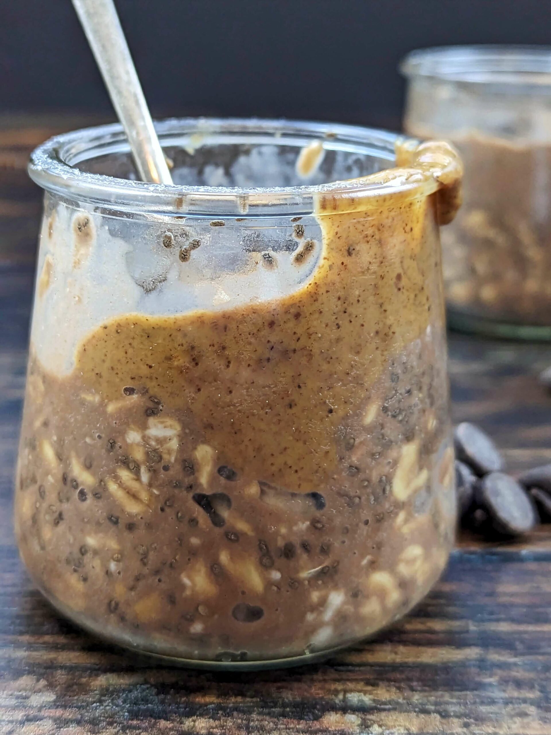 A container of protein overnight oats topped with almond butter and chocolate chips.