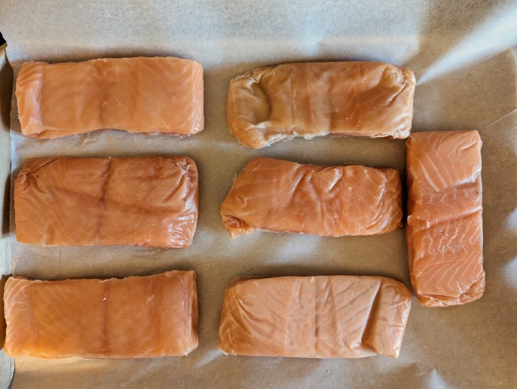 Sushi fillets lined onto a rimmed baking sheet.