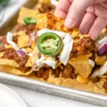 A tray of chili nachos topped with cheese, jalapeños, and onion.