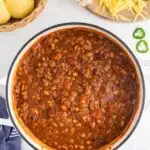 A serving bowl of chili surrounded by bowls of toppings.