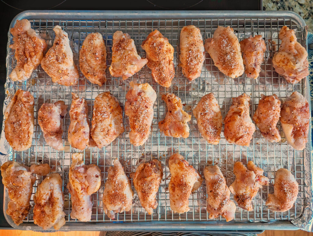 Chicken wings lined onto a rimmed baking sheet.