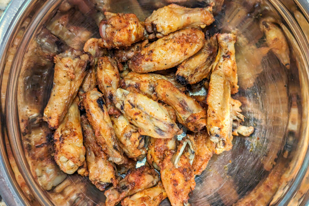 Wings tossed with garlic butter sauce in a bowl.