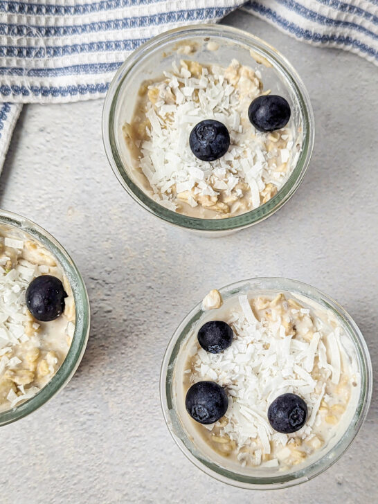 Three containers of overnight oats with coconut milk topped with fresh blueberries.