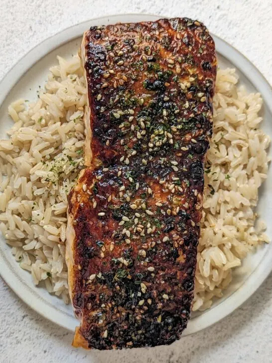 A fillet of furikake salmon served on a bed of rice.