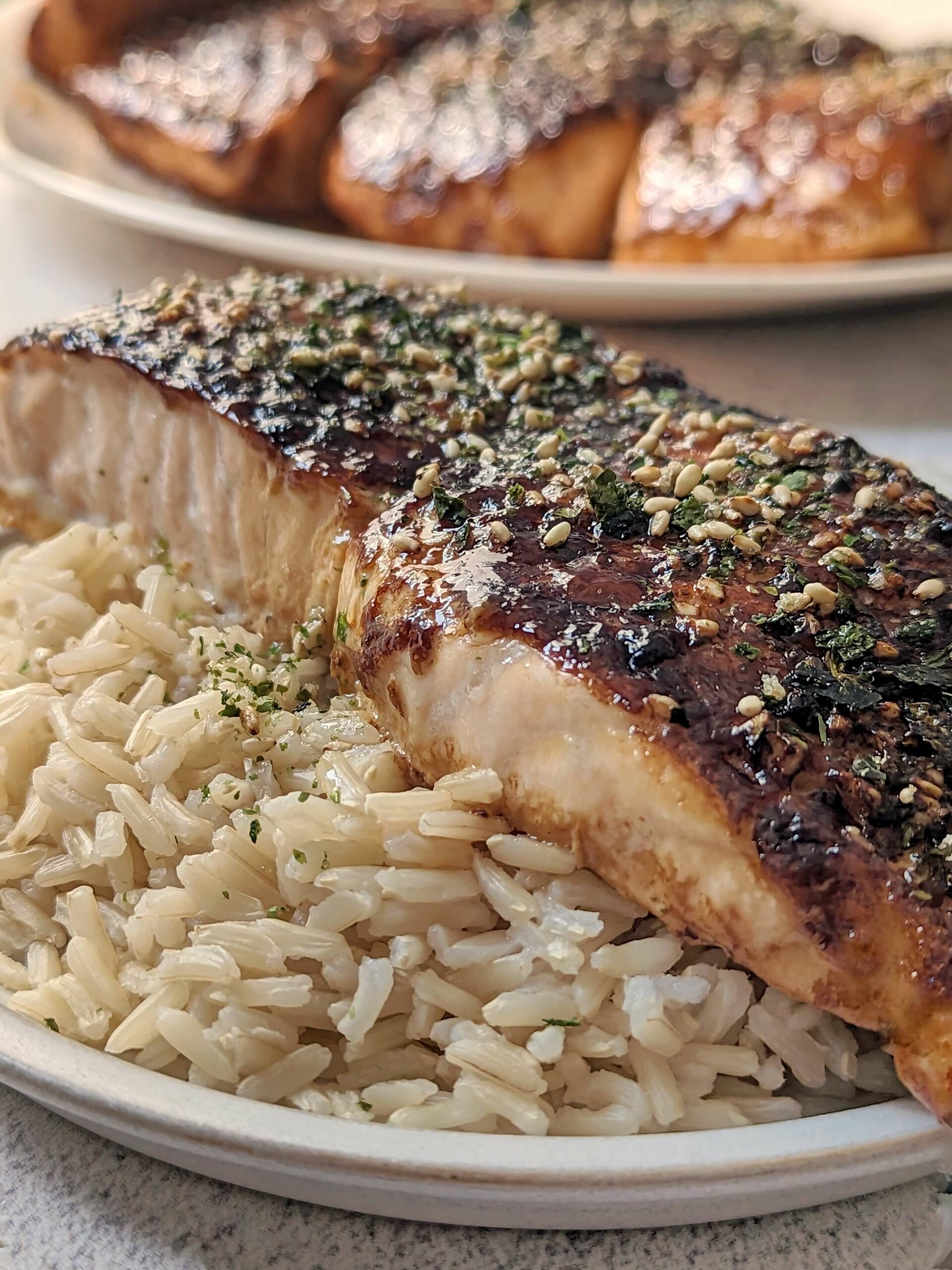 A fillet of furikake salmon served on a bed of rice.