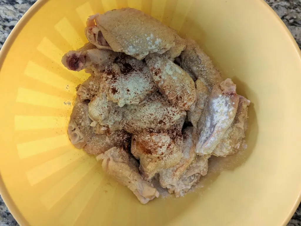 Wings in a mixing bowl with spices. 