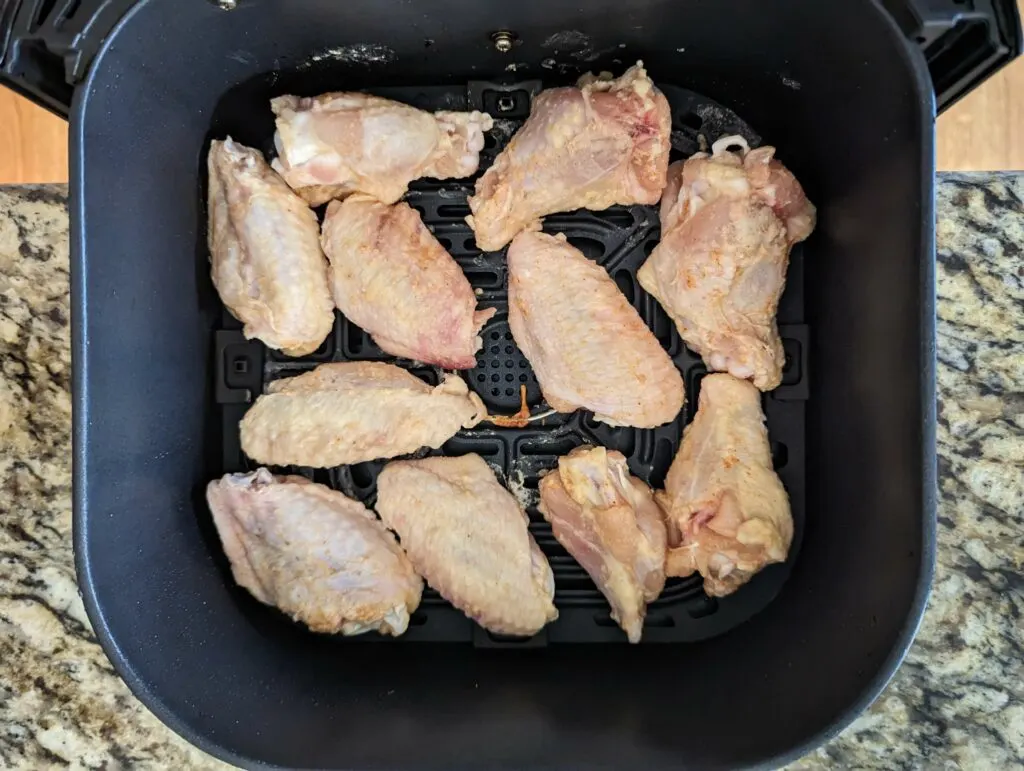 Chicken wings in an air fryer basket. 