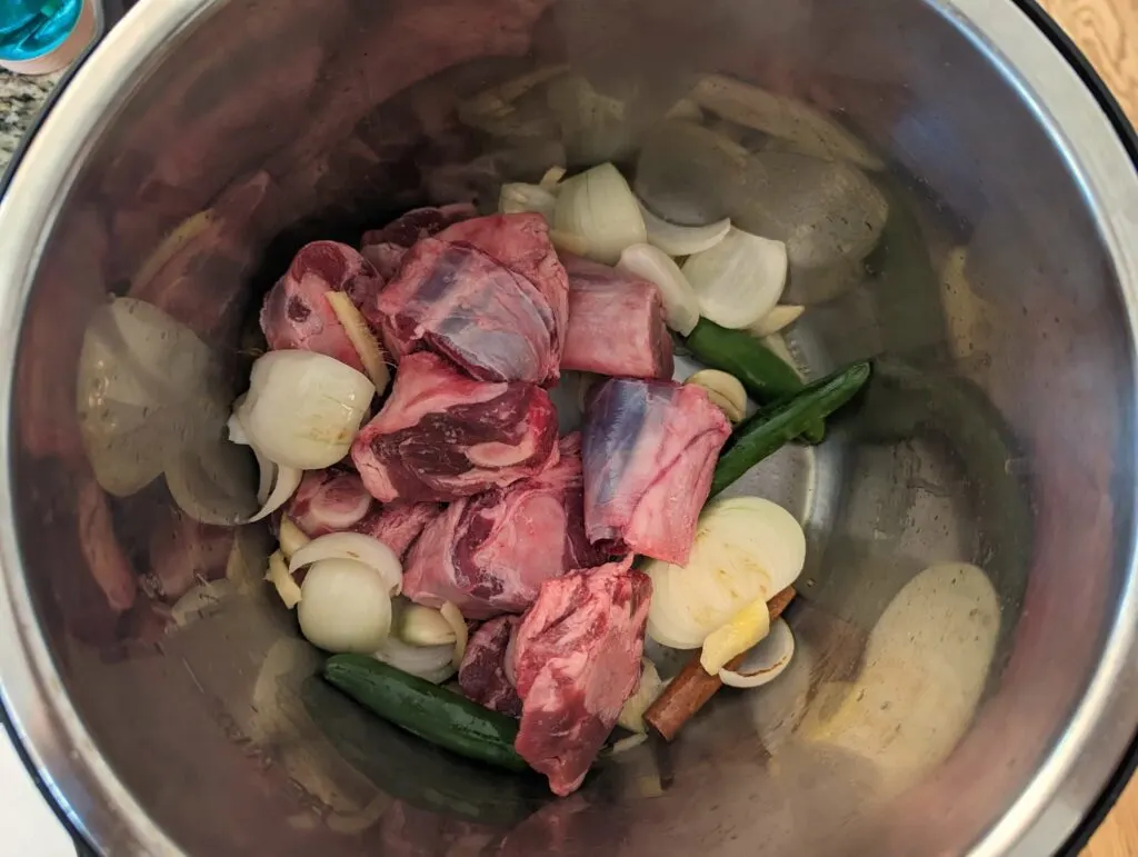 Mutton added to the onions and aromatics in the Instant Pot.