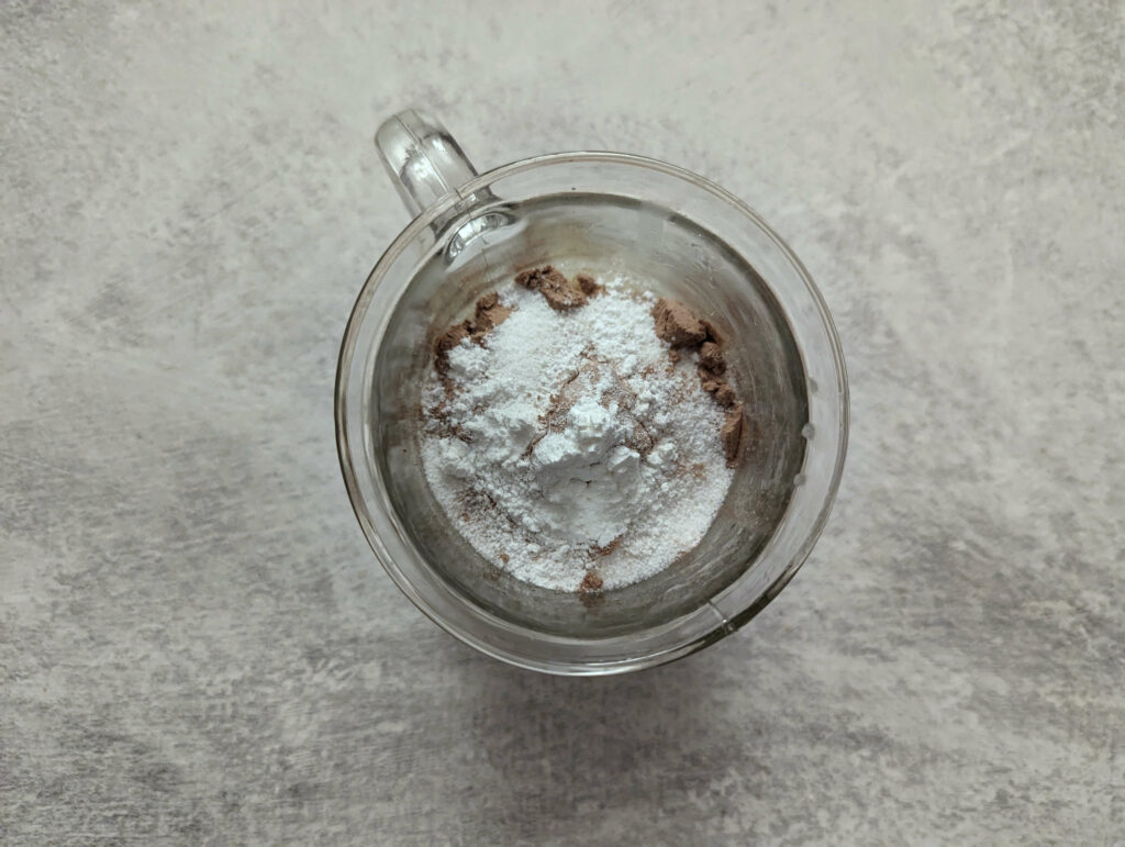 Dry ingredients added to wet ingredients in a mug.