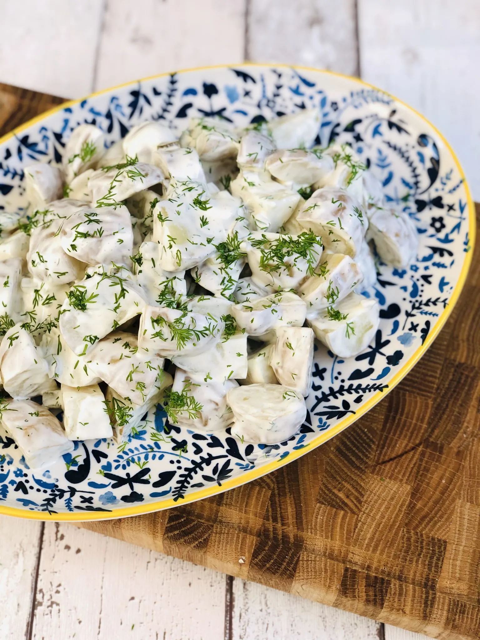 A serving dish of potato salad garnished with herbs.