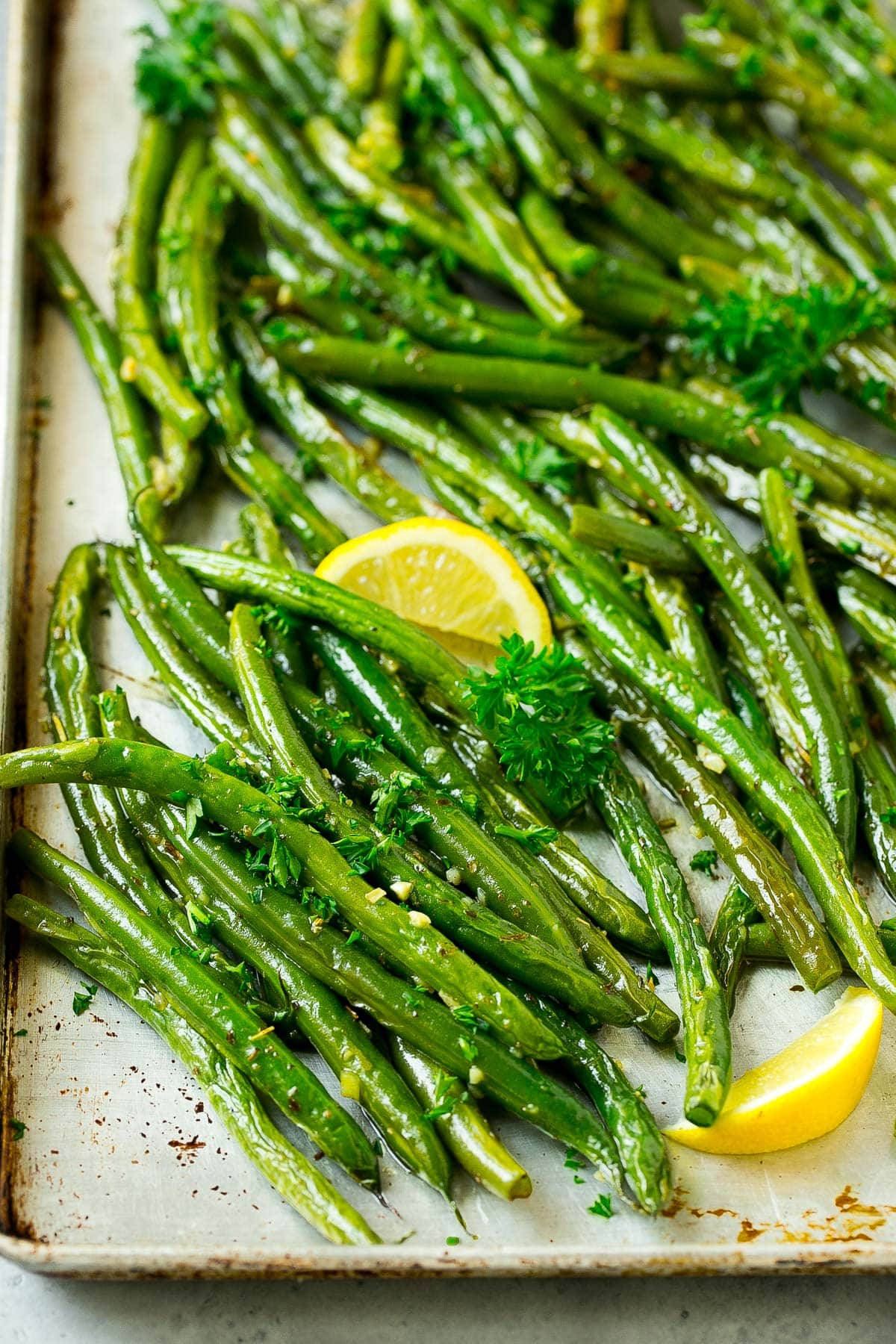 A close up of green beans and lemon wedges.