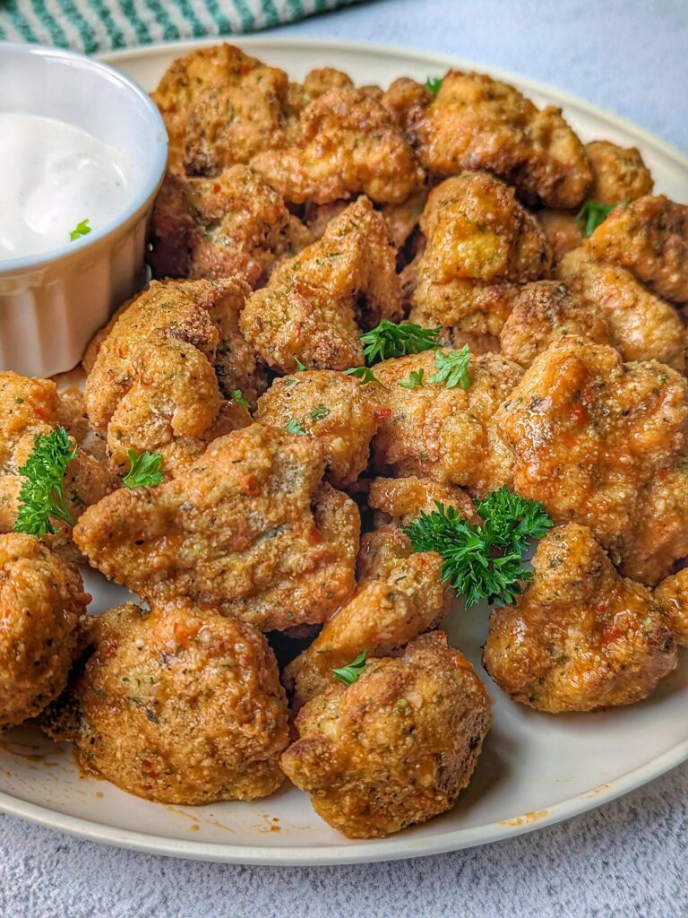 A plate of crispy cauliflower bites with a side of ranch.