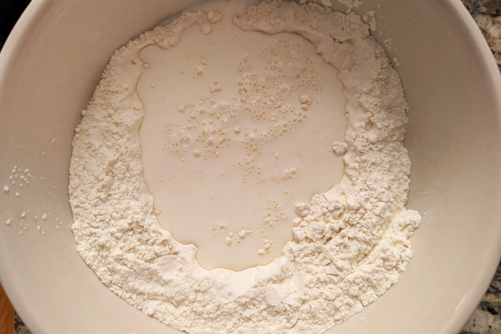 Wet ingredients added to the flour mixture in a bowl.