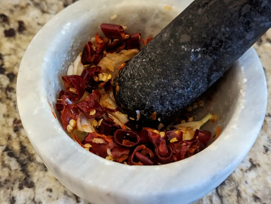 Ingredients for the pad cha paste in a mortar and pestle. 