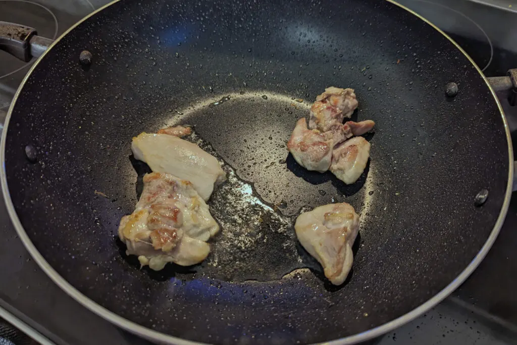 Chicken searing in a wok.