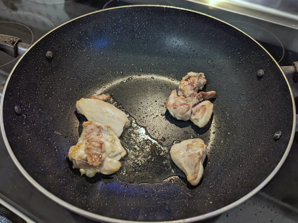 Chicken searing in a wok with oil