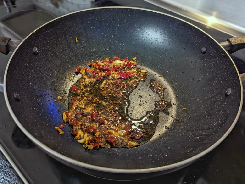 Garlic and chilies cooking in a wok with oil.