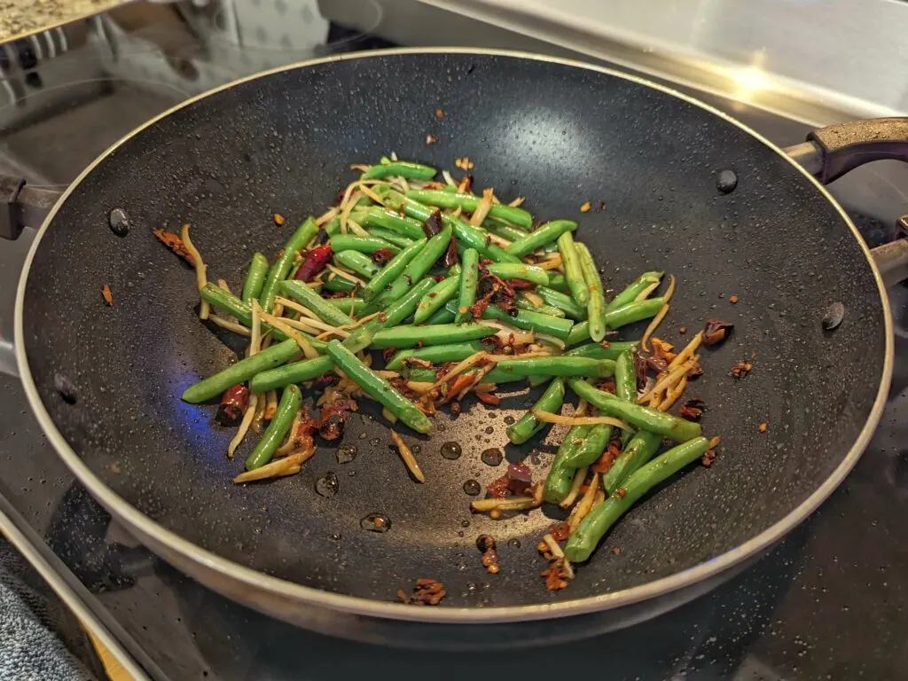 Krachai roots added to the other vegetables and chilies in a wok.