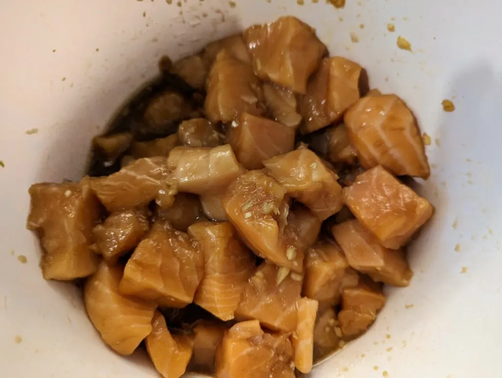 Salmon pieces marinating in a bowl.
