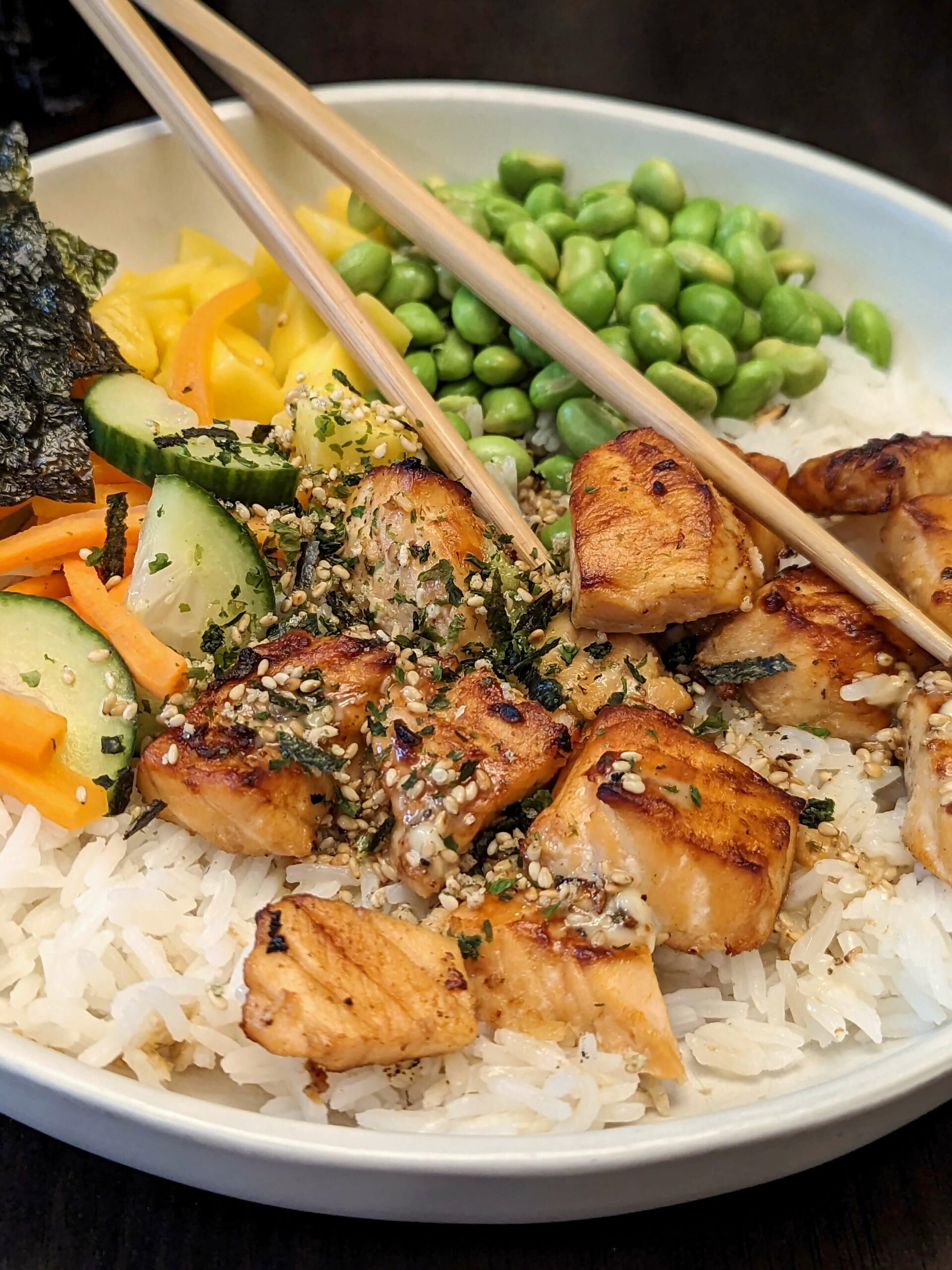 A close up of a sesame salmon bowl with seaweed.