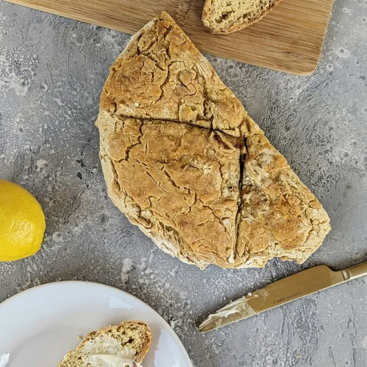 A loaf of soda bread without buttermilk and slices in the front.
