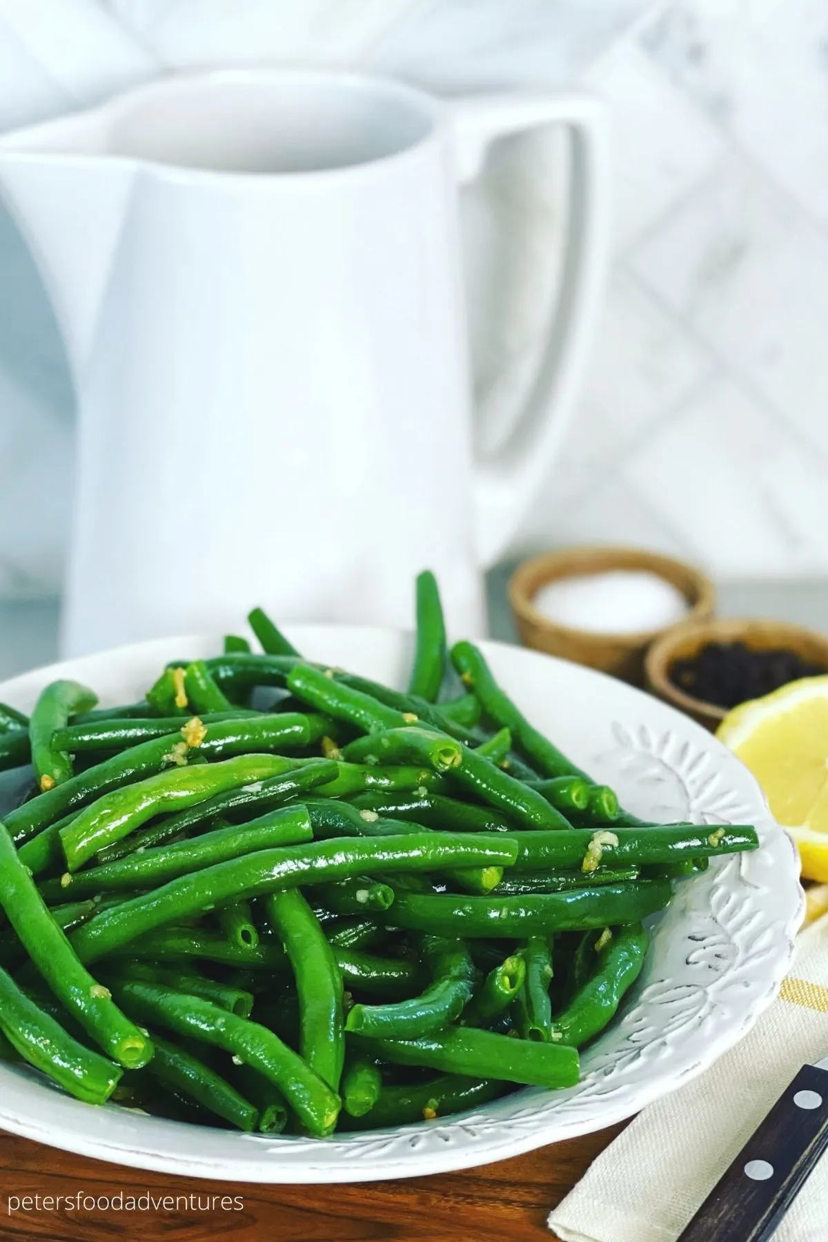 A close up of green beans with serving dishes in the background.