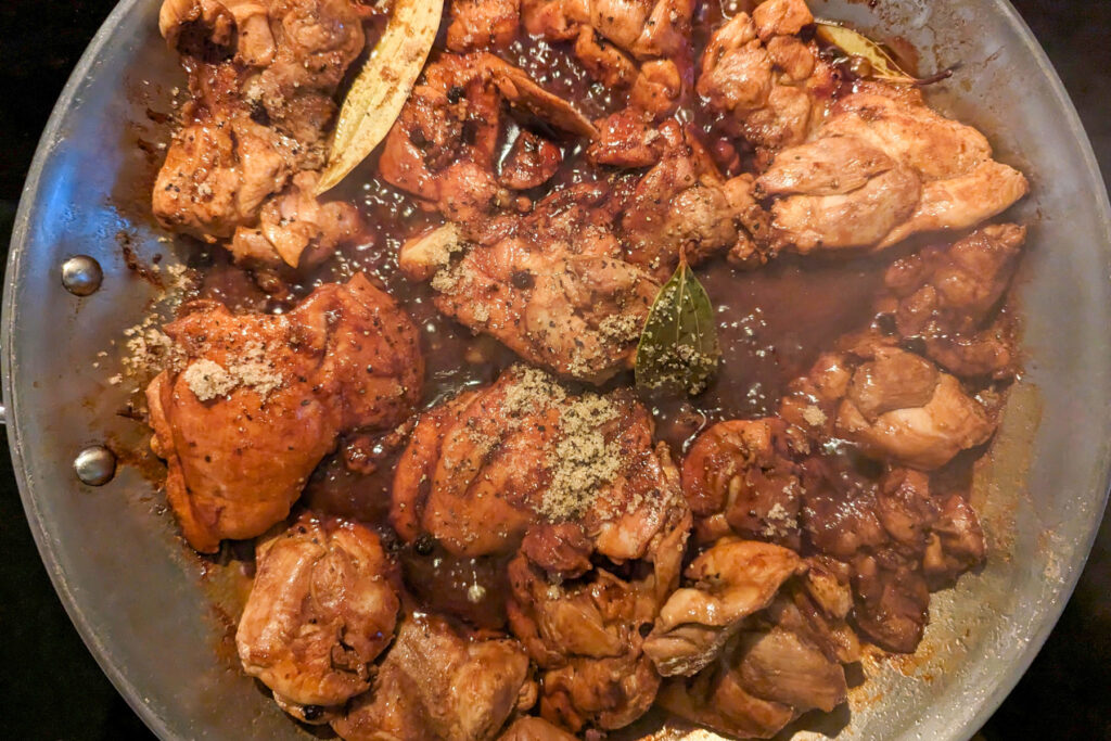 Chicken thighs braising in a pan.