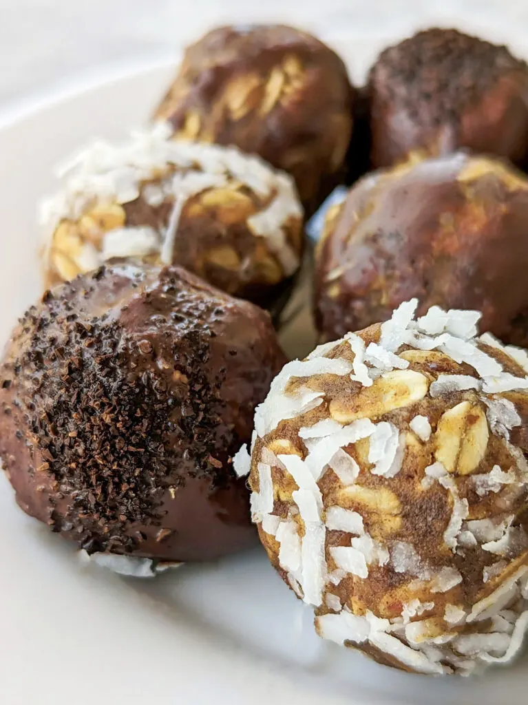 A close up of the pumpkin protein balls. Some of them are tossed with chocolate, chocolate and espresso powder, and coconut flakes.