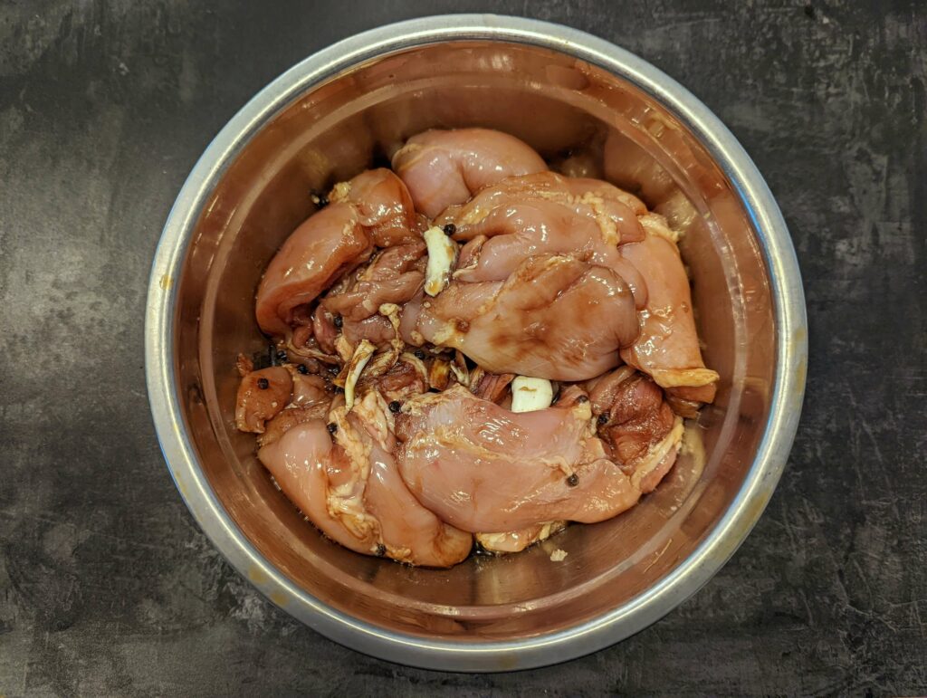 Chicken thighs marinating in a mixing bowl.