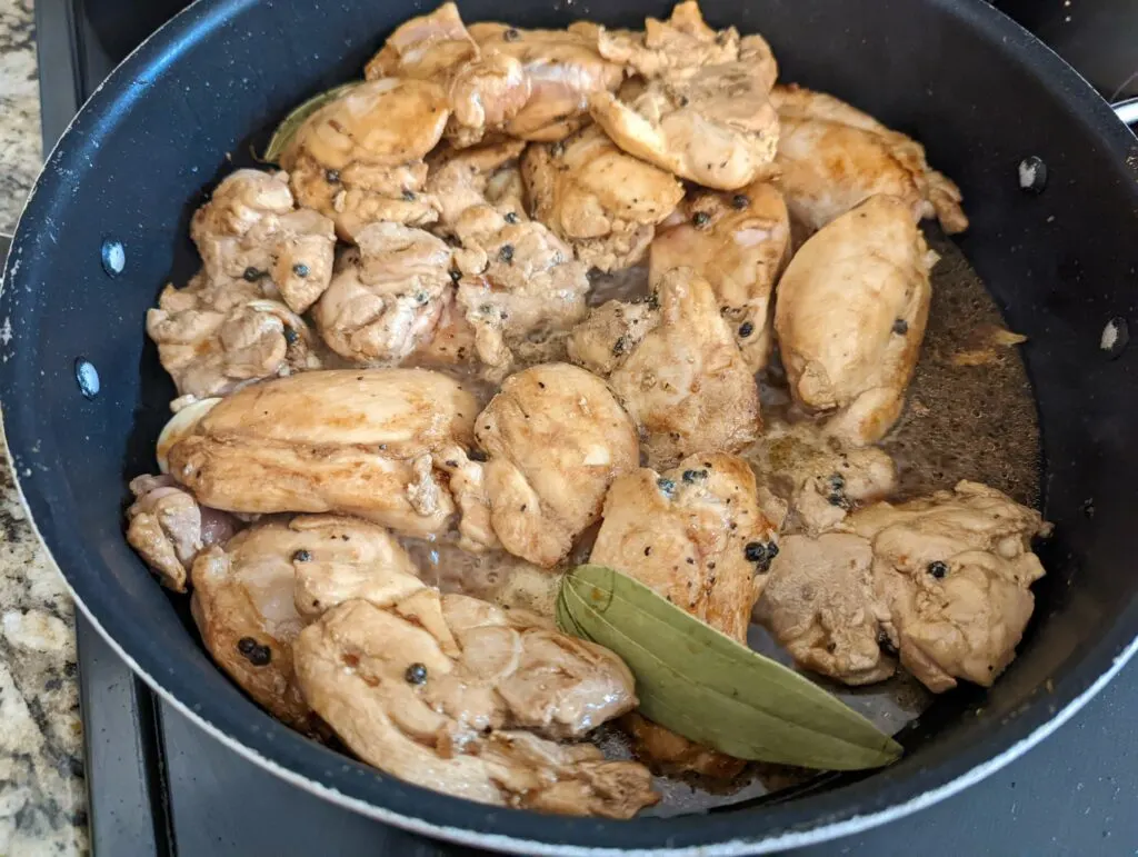 Chicken thighs returned to the pan to simmer.