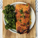 Cajun honey butter salmon on a plate with broccolini.