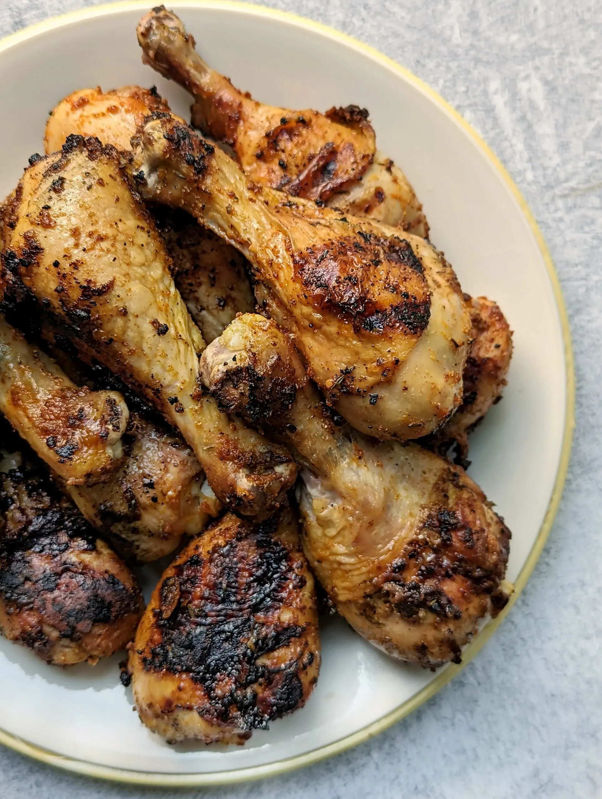 A plate full of grilled chicken drumsticks each with a perfect char.