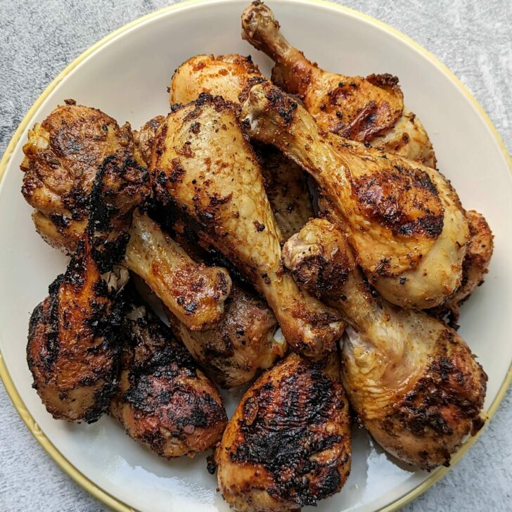 A plate full of grilled chicken drumsticks each with a perfect char.