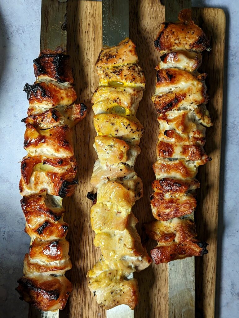 A close up of joojeh kabobs on skewers.